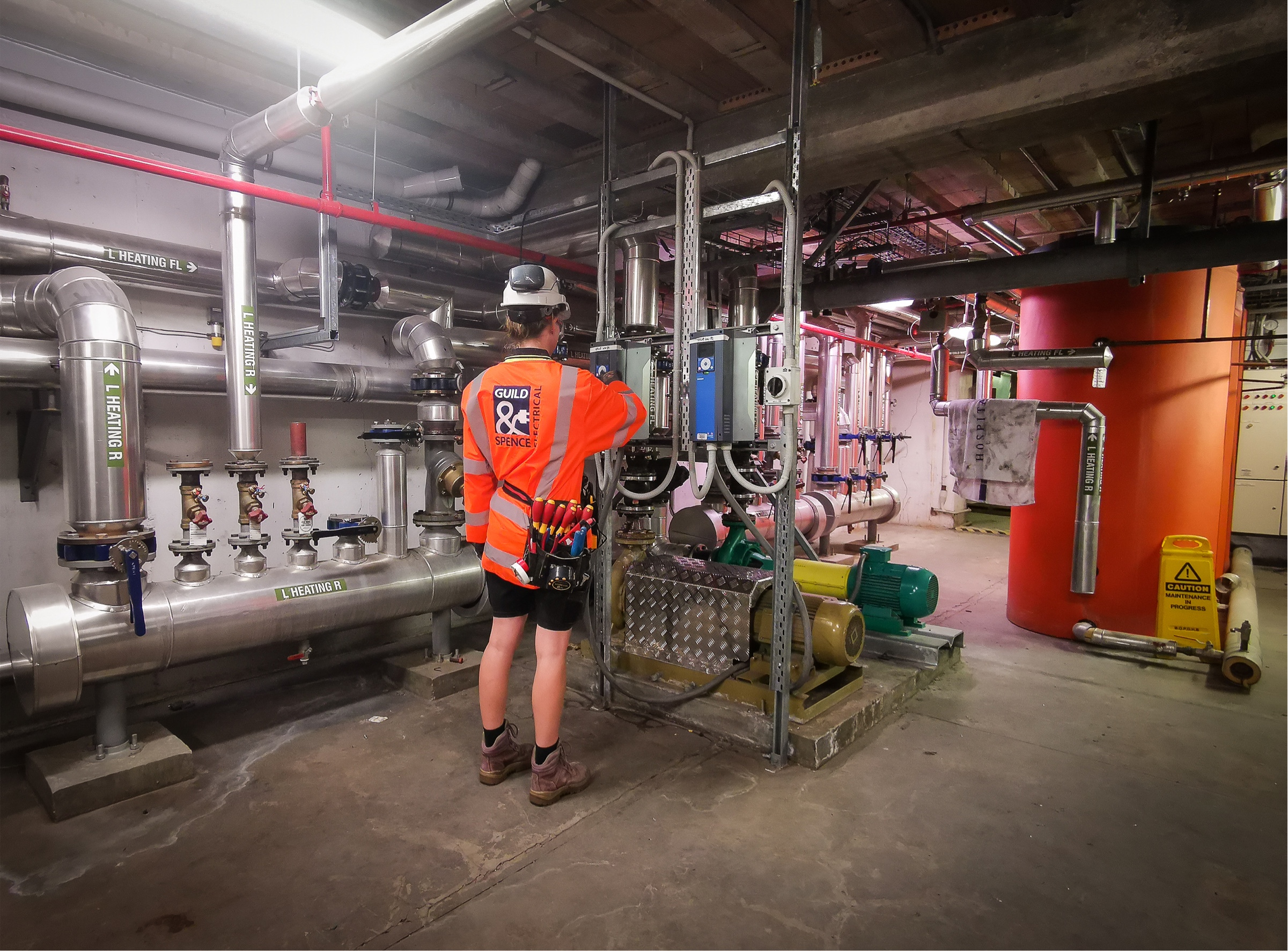 An electrician adjusting electrical panels in a work room.