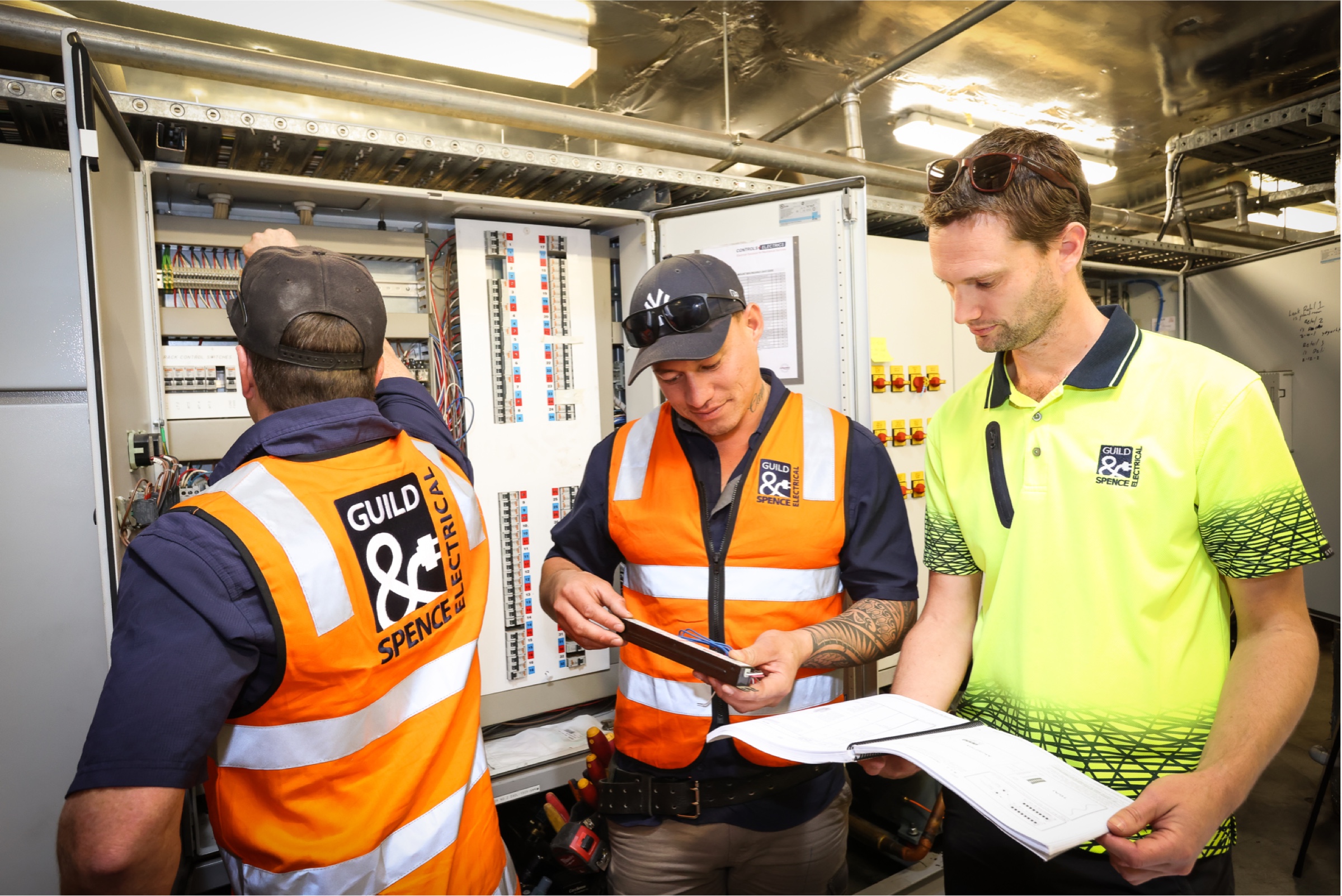 Guild & Spence employees reviewing schematics for an electrical box.