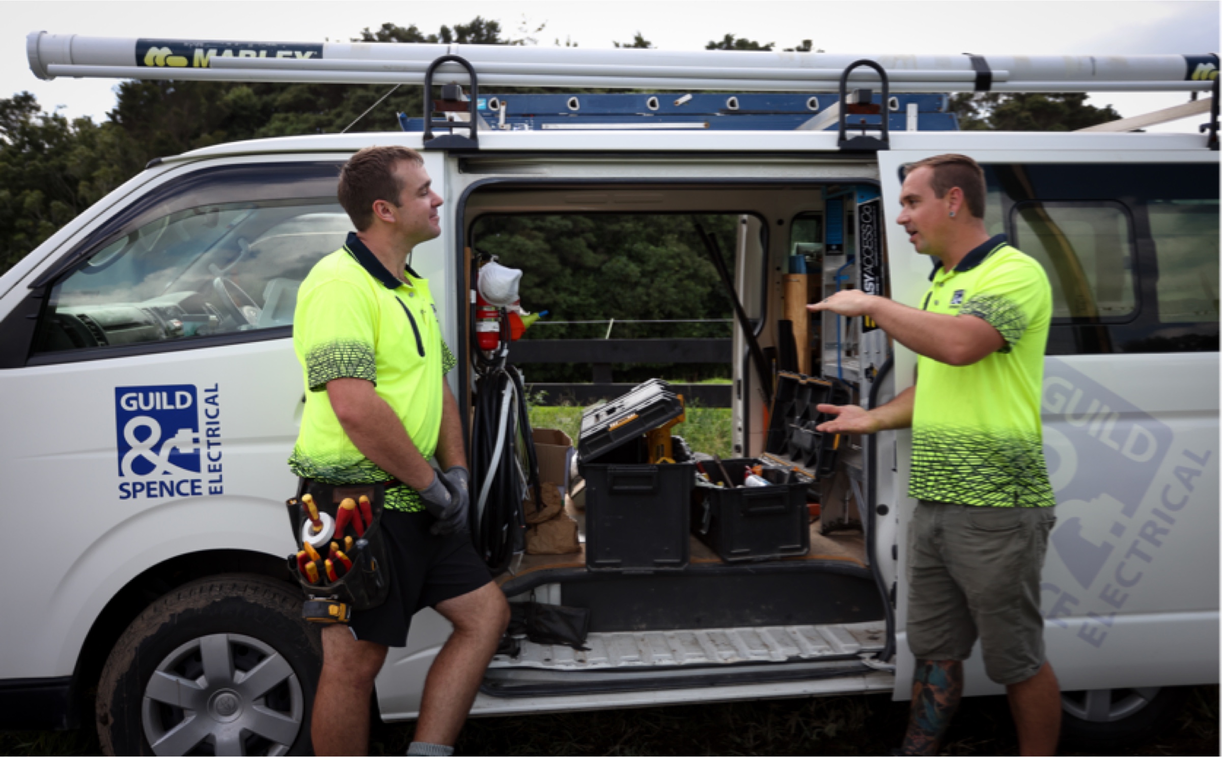 Electricians standing in front of a work van.
