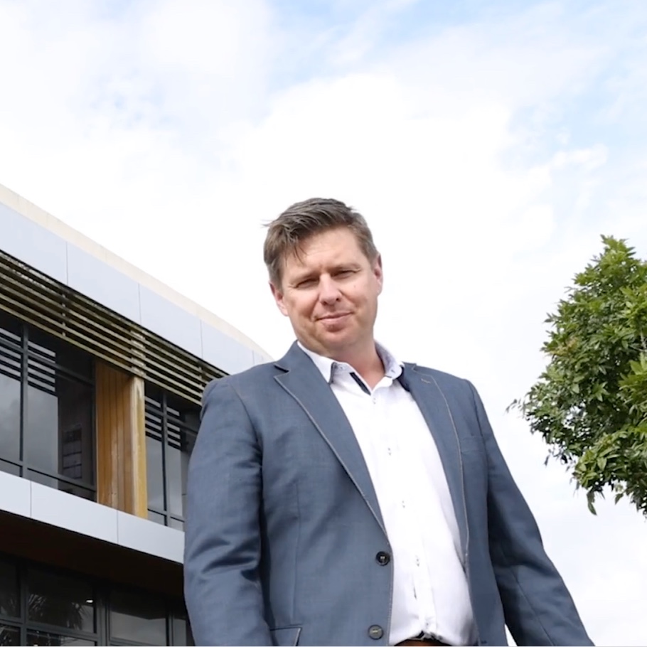 A man in a suite stands outside a modern office building.